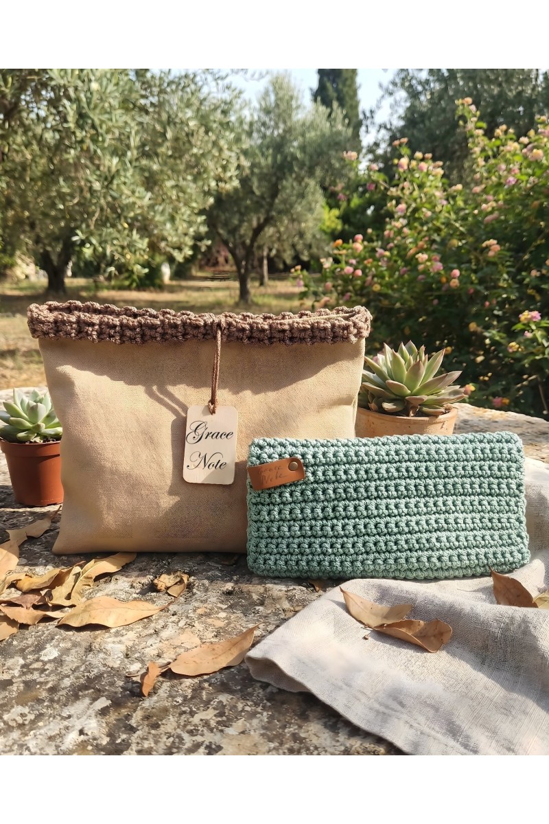 Grace Note Menta handmade crochet wallet displayed in a Mediterranean garden